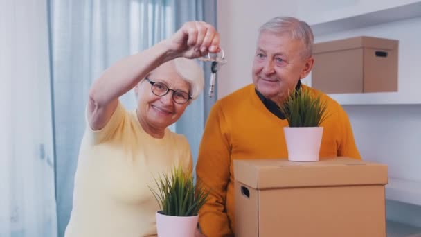Kvinnan med husnycklar och mannen med pappkartonger. Äldre par köper nytt hem. — Stockvideo