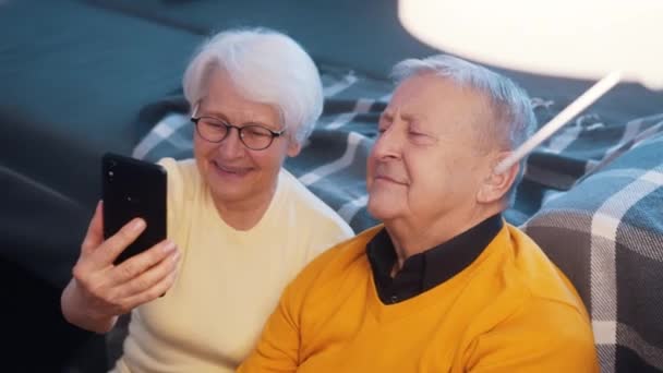 Счастливая пара на пенсии бабушка и дедушка делают селфи на смартфоне или видео-звонок с семьей. — стоковое видео