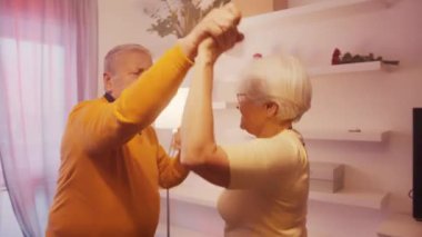 Otel odasında disko ışıklarıyla dans eden mutlu yaşlı çift. Sevgililer Günü ya da yıldönümü kutlaması