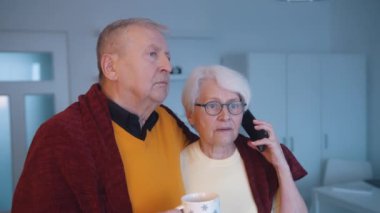 Yaşlı bir çift televizyon izlerken sarılıyor ve telefonda konuşuyor.. 