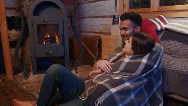 Vinterlov. Glada unga par som kopplar av nära öppna spisen — Stockvideo