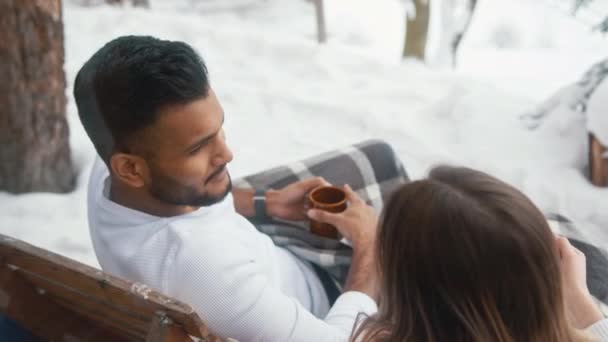 Feliz pareja joven bebiendo chocolate caliente en el balcón en el día de invierno. Navidad o día de San Valentín. Disparo aéreo — Vídeos de Stock