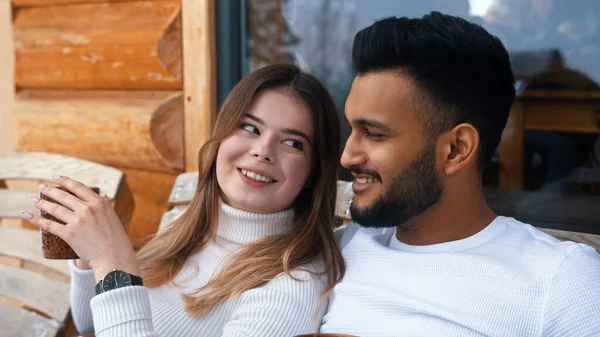 Sluit maar af. Gelukkig jong stel knuffelen bedekt met deken op de buitenbank. Warme drank drinken en genieten van sneeuw — Stockfoto