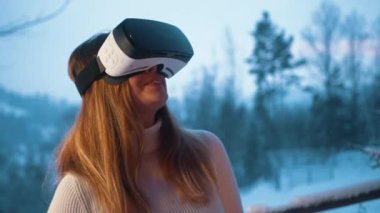 Kışın karlı bir günde açık havada VR gözlük takan beyaz bir kadın.