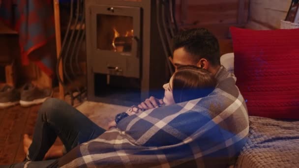 Par som sitter vid den brinnande öppna spisen i ett mysigt hus — Stockvideo