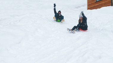 Genç çift Noel tatilinde karda kızakla geziyor.