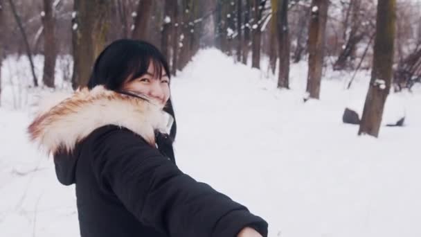 Retrato de jovem mulher asiática levando seu namorado para o parque coberto de neve — Vídeo de Stock