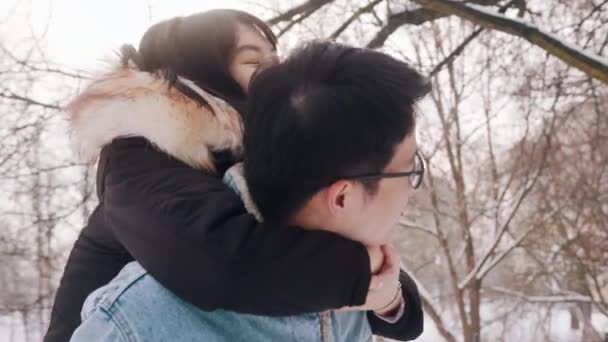 Nygift asiatisk par have det sjovt udenfor på Valentinsdag. Ung mand giver piggyback ride til sin kæreste – Stock-video