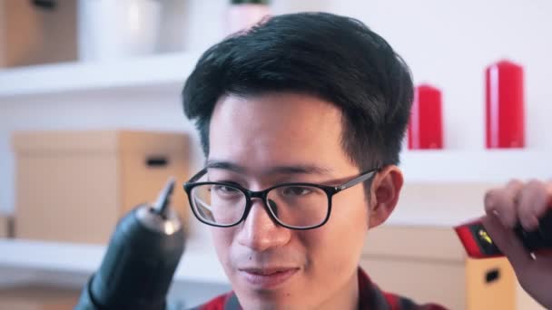 Zdezorientowany Azji człowiek z okulary gospodarstwa wiertarka — Wideo stockowe