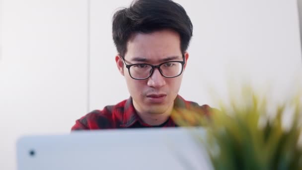 Giovane sconvolto asiatico uomo working su il laptop a casa — Video Stock