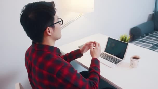 Молодой азиат, растянувшись на стуле, доволен своей работой — стоковое видео