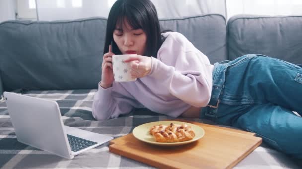 Jeune femme asiatique parlant au téléphone tout en buvant du café et en mangeant le petit déjeuner — Video