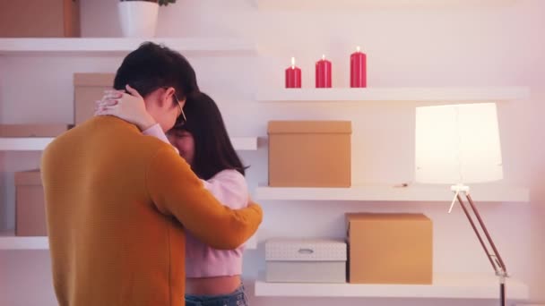 Joyeuse Saint Valentin. Jeune couple asiatique dansant et se câlinant dans un nouveau compartiment. Boîtes en carton sur l'étagère — Video