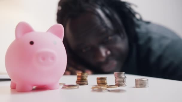 El hombre cuenta sus ahorros. Primer plano de la alcancía rodeada de monedas — Vídeo de stock