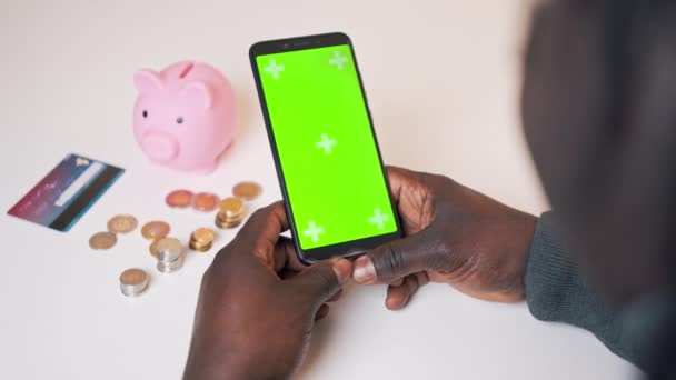 Смартфон с зеленым экраном. Африканский черный мужчина использует мобильное приложение для инвестирования — стоковое видео
