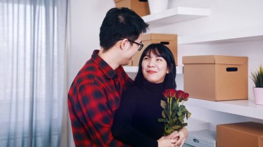 Mutlu yıldönümleri Koca, yeni dairesinde karısına sarılıyor. Kırmızı güller tutan kadın
