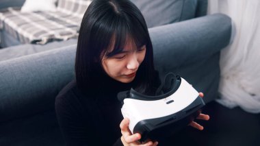 Elinde sanal gerçeklik gözlüğü olan Asyalı bir kadın..