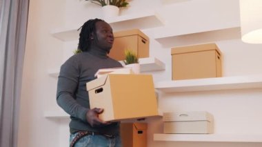 Karton kutularla Afrika kökenli siyahi bir adam yeni daireye taşınıyor.