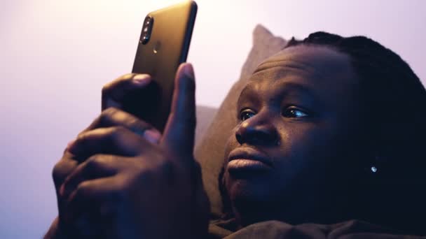 아프리카 계 미국인 흑인 남자가 소파에서 쉬는 동안 스마트폰을 사용하는 모습 — 비디오