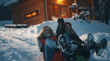 Karlı kış akşamında kızaklarda kayan iki kız. Kış mevsimi, Noel tatili