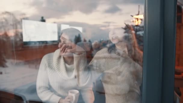 Zwei Mädchen blicken aus dem Fenster auf verschneite Nachbarschaft — Stockvideo