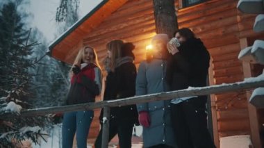 Kış tatilindeki en iyi arkadaşlar. Dağdaki ahşap evin önünde sıcak çikolata içmek.