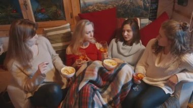 Genç kadınlar kış tatillerini battaniyeyle örtülü olarak sıcak şarap içerek ve abur cubur yiyerek geçirirler.