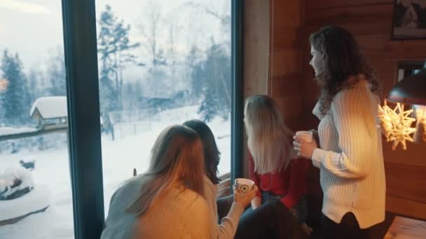 Jovens senhoras olhando pela janela na montanha coberta de neve. Férias de inverno — Vídeo de Stock