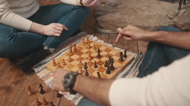 De cerca. Pareja joven jugando al ajedrez en el suelo de la acogedora casa — Vídeo de stock