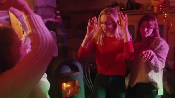 Mujeres jóvenes felices haciendo una fiesta, bailando en la acogedora casa. Vacaciones de invierno — Vídeos de Stock