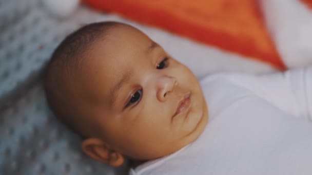 Portrait of cute mulatto baby with funny face expression relaxing on the blanket — Stock Video