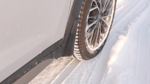 Zbliżenie na samochód pędzi przez śnieg z opon zimowych pozostawiając za sobą parę. Niebezpieczne dla drogi — Wideo stockowe