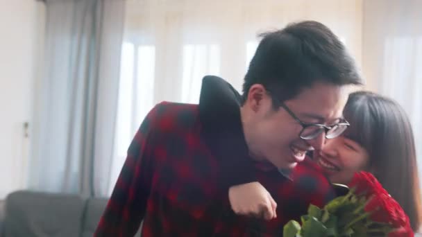 Молодий азіатський чоловік дивує свою дівчину букетом червоних троянд — стокове відео