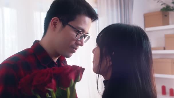 Feliz joven asiática pareja besándose detrás del ramo de rosas rojas — Vídeos de Stock