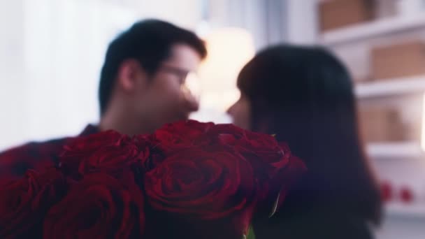 Feliz joven asiática pareja besándose detrás del ramo de rosas rojas — Vídeos de Stock