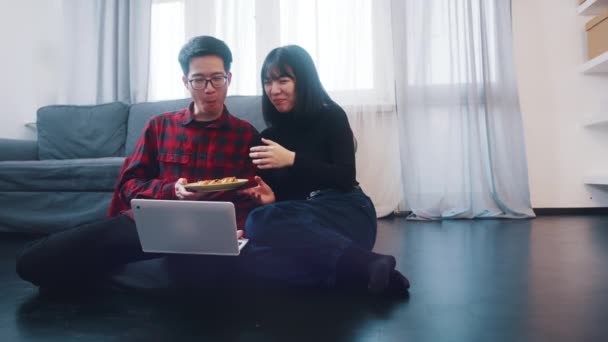 Jovens casais felizes assistindo filmes no laptop ou navegando nas mídias sociais com lanche — Vídeo de Stock