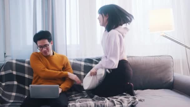 Молодая женщина ищет внимания своего парня, который работает на ноутбуке — стоковое видео