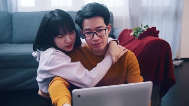 Feliz jovem casal relaxante no sofá abraçando e assistindo filme no laptop — Vídeo de Stock