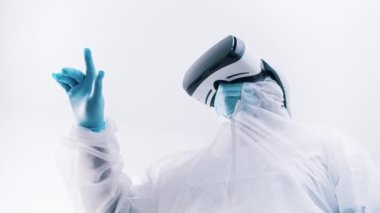 Gözlüklü, koruyucu üniformalı ve parmaklarıyla havaya dokunan tanınmayan bir doktor. Robot cerrahi simülasyonu