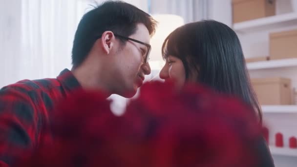 Молода азіатська пара цілується за букетом червоних троянд. Молода любов і сімейне життя — стокове відео