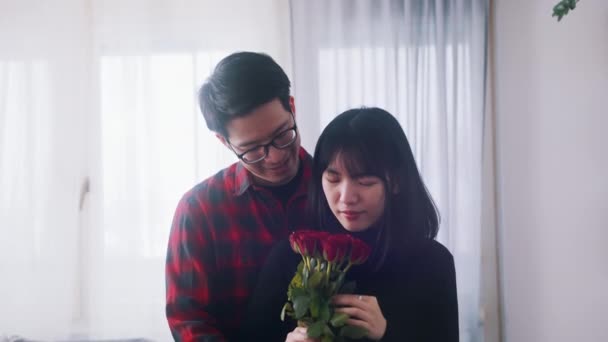 Молодий азіатський чоловік дарує червоні троянди своїй дівчині. Любов романтика і пропозиція — стокове відео