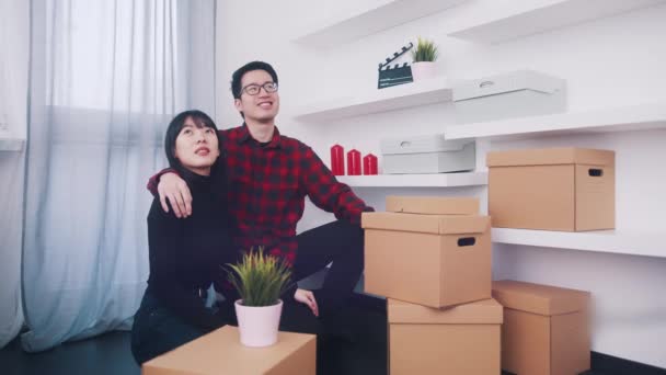 Feliz joven pareja asiática mudándose en el nuevo apartamento. Rodeado de cajas de cartón — Vídeo de stock