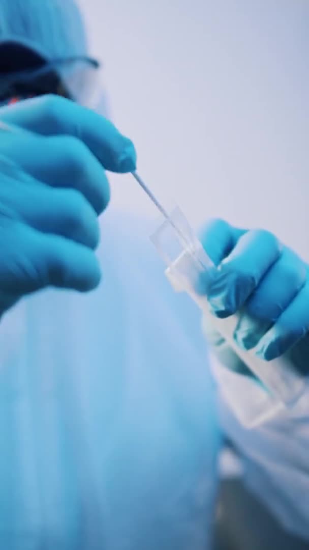 Vertikal. Dokter dalam seragam perlindungan penuh membuka jarum untuk vaksinasi terhadap covid-19 — Stok Video