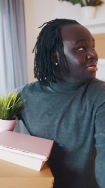 Dikey. Yeni ev sahibi. Siyahi bir adam yeni evinden bir video görüşmesi yapıyor.