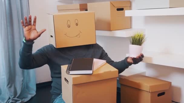 Hombre negro irreconocible con caja de cartón en la cabeza bailando en nuevo apartamento — Vídeos de Stock