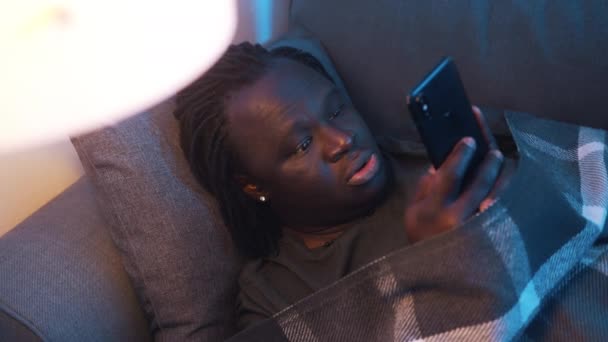 Ένας καταθλιπτικός Αφροαμερικάνος μαύρος διαβάζει email τυλιγμένο σε κουβέρτα. Άσχημα νέα. — Αρχείο Βίντεο