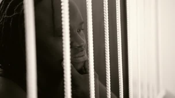 Jailed african american black man rubbing his chin behind bars — Stock Video