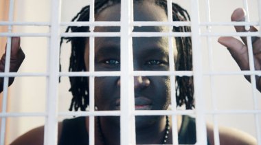 Hapishanede parmaklık tutan Afrikalı Amerikalı siyahi adamın portresi.