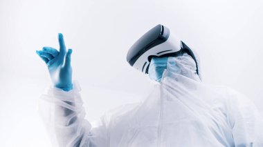 Gözlüklü, koruyucu üniformalı ve parmaklarıyla havaya dokunan tanınmayan bir doktor. Robot cerrahi simülasyonu