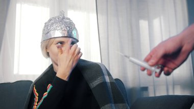 Covid-19 aşısını reddeden alüminyum folyolu bir kadın. covid-19 salgını ve 5G ağı arasındaki bağlantı hakkında komplo teorisi
